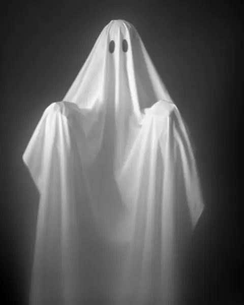 Person Wearing A Ghost Costume, Made Out Of A White Sheet With Two Holes In It