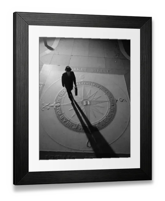 Framed Print : Silhouetted businessman with briefcase walking across compass in the sidewalk Framed Print : Silhouetted businessman with briefcase walking across compass in the sidewalk