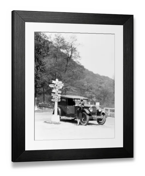 Framed Print : Woman leaning on car looking at road map and signs with arrows pointing to selected towns Framed Print : Woman leaning on car looking at road map and signs with arrows pointing to selected towns