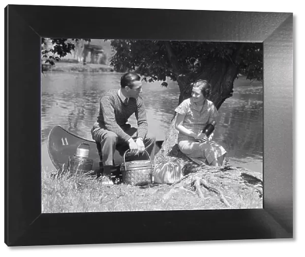 Couple Young Man Woman Smiling In Front Of Canoe With Picnic Basket Thermos Man Sweater