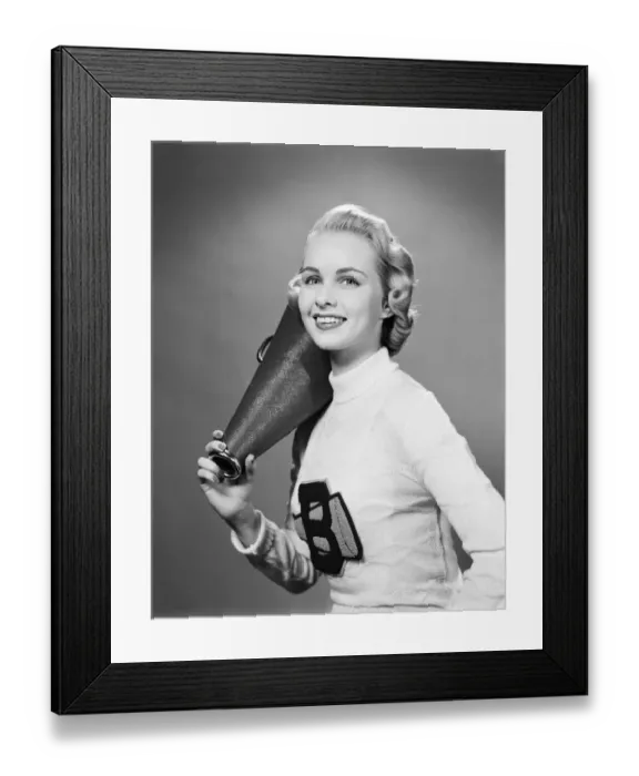 Framed Print : Teenage girl wearing cheerleader sweater holding megaphone over shoulder