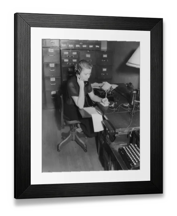 Framed Print : Secretary sitting at desk behind typewriter, on phone taking message Framed Print : Secretary sitting at desk behind typewriter, on phone taking message