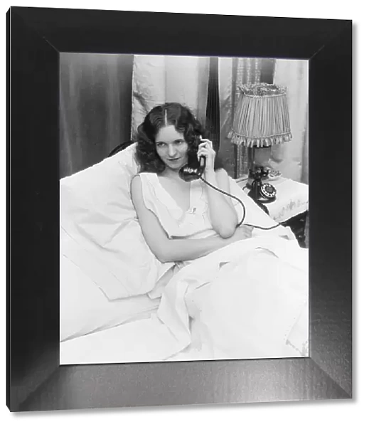 Woman sitting in bed, talking on phone