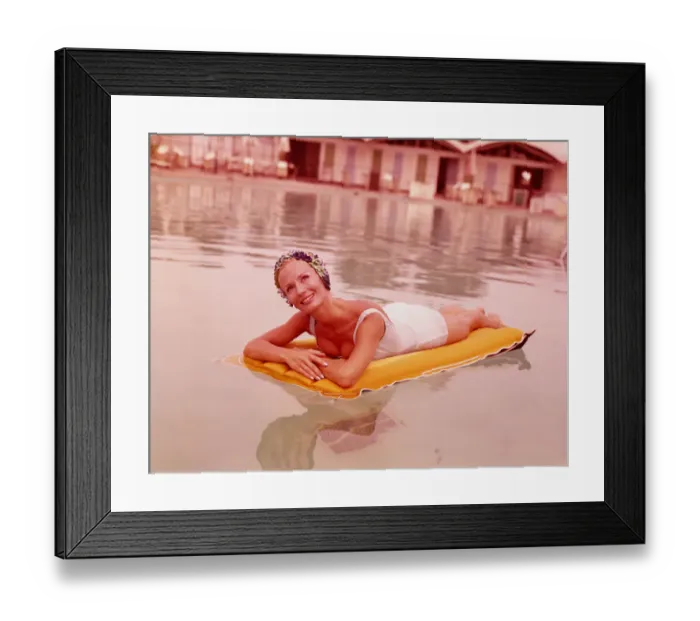 Framed Print : Woman in swimming pool reclining on inflatable raft, wearing bathing cap, smiling Framed Print : Woman in swimming pool reclining on inflatable raft, wearing bathing cap, smiling