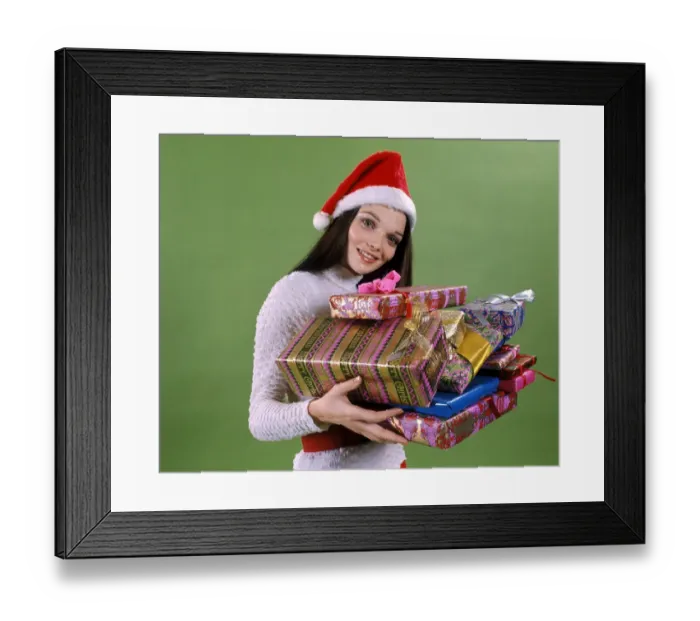 Framed Print : Young woman wearing santa hat, holding armful wrapped presents Framed Print : Young woman wearing santa hat, holding armful wrapped presents