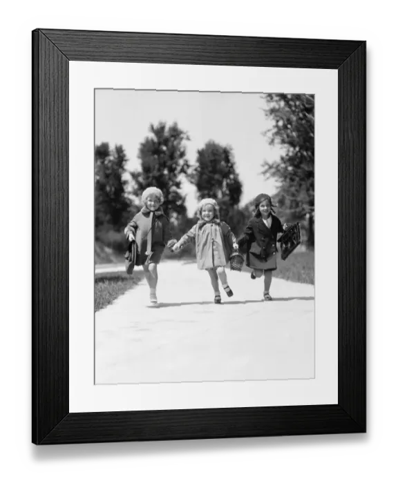 Framed Print : Three girls running along suburban sidewalk wearing fall weather coats and hats