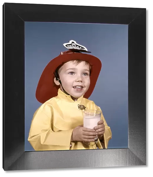 Boy in fireman costume, holding a glass of milk