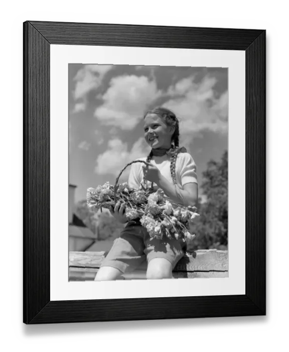 Framed Print : Farm girl with pigtails, sitting on fence, holding basket of flowers, smiling Framed Print : Farm girl with pigtails, sitting on fence, holding basket of flowers, smiling