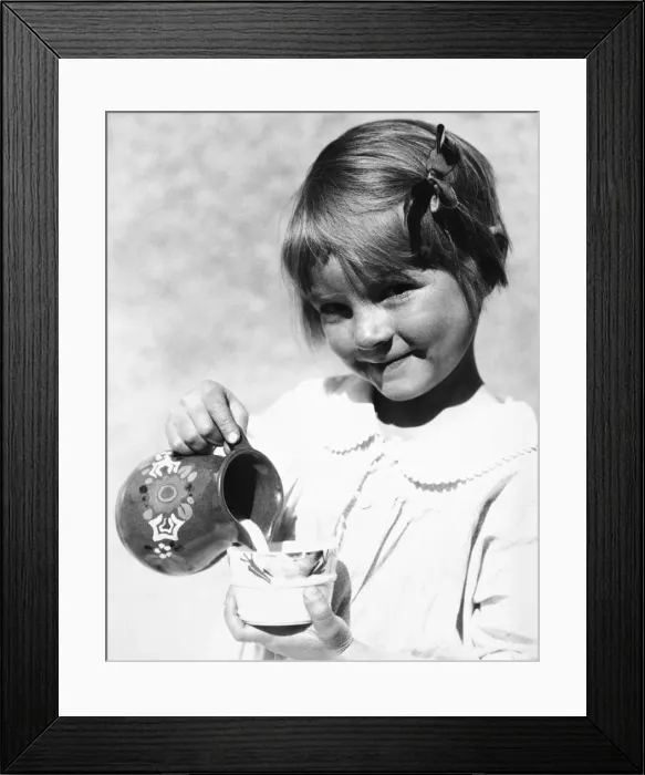 Framed Print : Girl poring milk from pitcher into cup Framed Print : Girl poring milk from pitcher into cup
