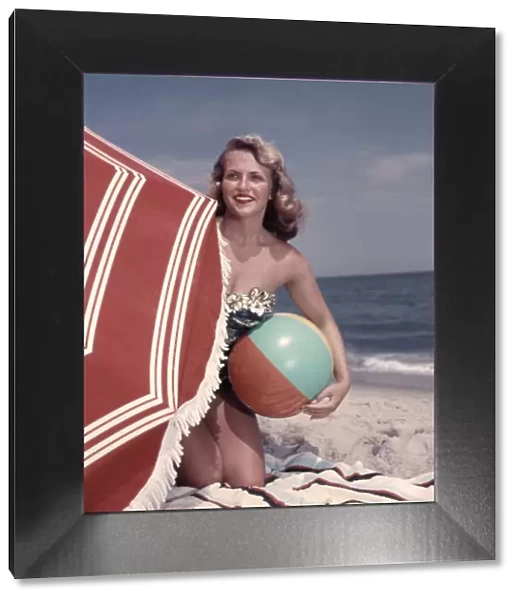 Smiling Blonde Woman Bathing Suit Hold Beach Ball Kneel In Sand By Red Sun Umbrella