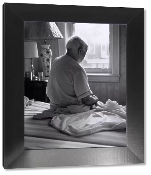 Senior man sitting on bed facing window
