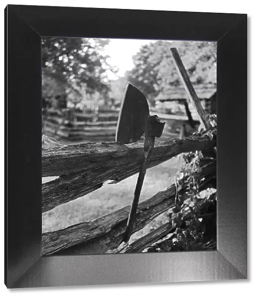 Broad Axe. circa 1956: A broad axe rests on a split-rail fence in the village of New Salem