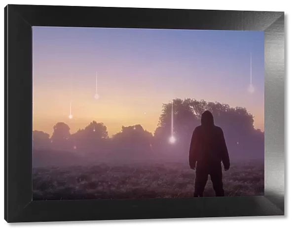 A UFO, supernatural concept. A hooded figure with his back to the camera