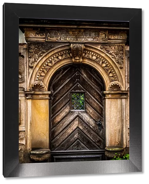 An old carved wooden door with an ornate frame with latin inscriptions