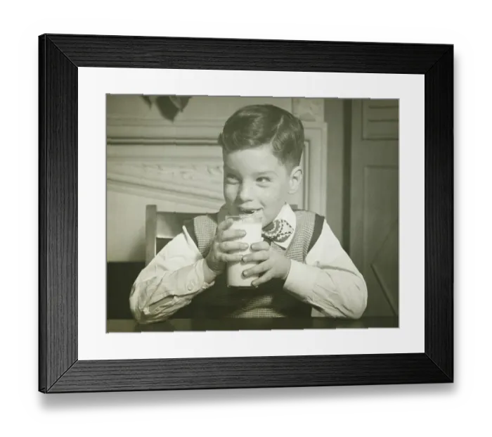 Framed Print : Boy (8-9) holding glass of milk, sitting at table, smiling, (B&W), close-up Framed Print : Boy (8-9) holding glass of milk, sitting at table, smiling, (B&W), close-up