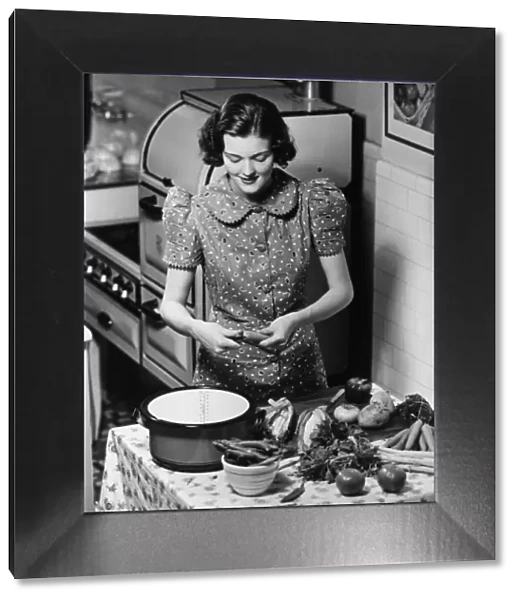 Young woman preparing vegetables in kitchen, (B&W), elevated view