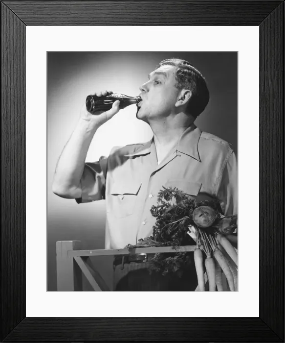 Framed Print : Man drinking cola from bottle in studio (B&W) Framed Print : Man drinking cola from bottle in studio (B&W)