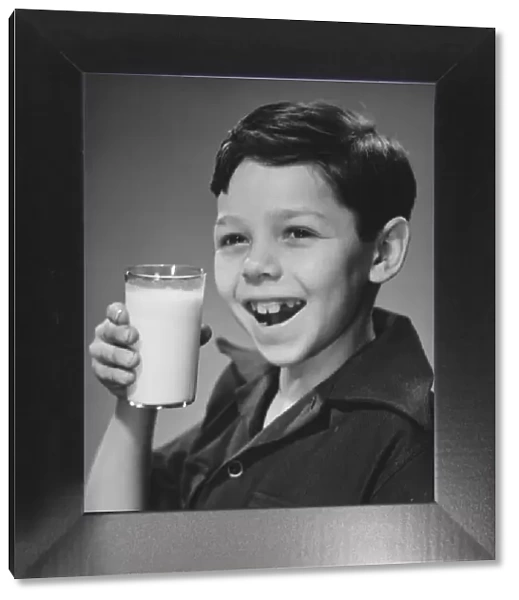Boy (8-9) holding glass of milk, smiling (B&W), portrait