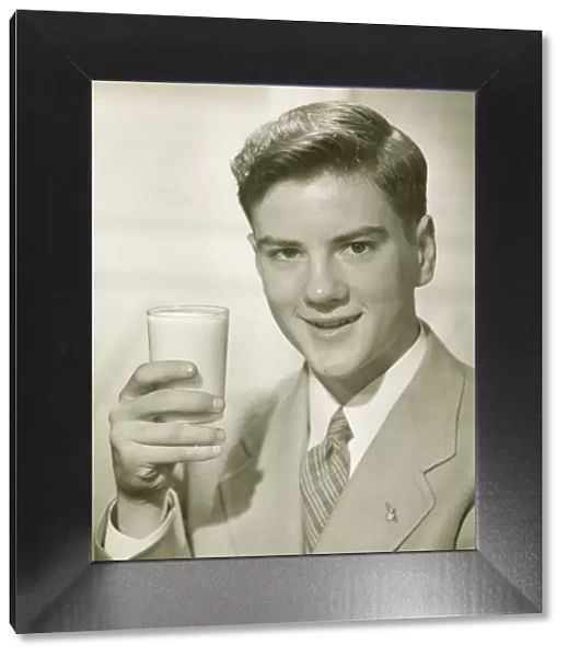 Young man holding glass of milk, (B&W), portrait