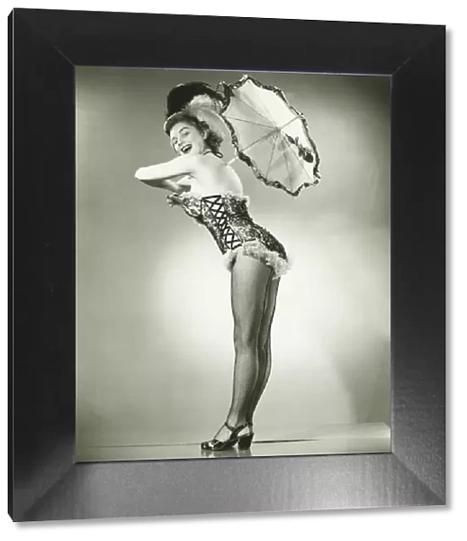 Young woman holding umbrella posing in studio, (B&W)