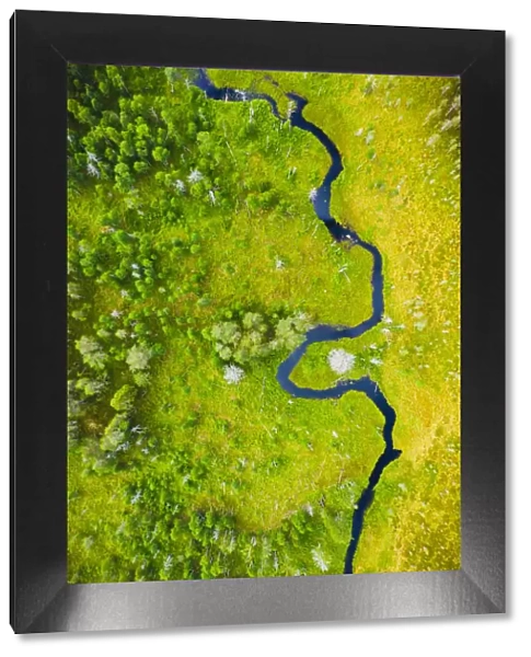 Aerial view of a small river flowing through marshland in Finland