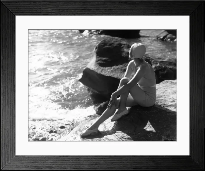 Framed Print : Lorelei. circa 1930: A swimsuited woman sits on a rock gazing out to sea Framed Print : Lorelei. circa 1930: A swimsuited woman sits on a rock gazing out to sea