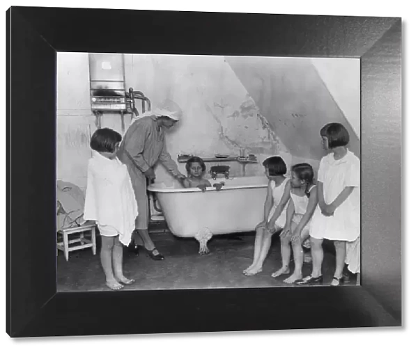 Bath Time. circa 1930: Bath time for a group of young girls