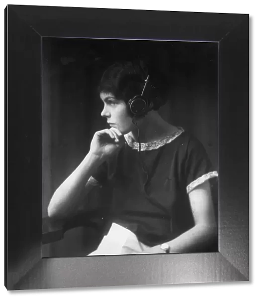Listener. circa 1930: A girl wearing headphones