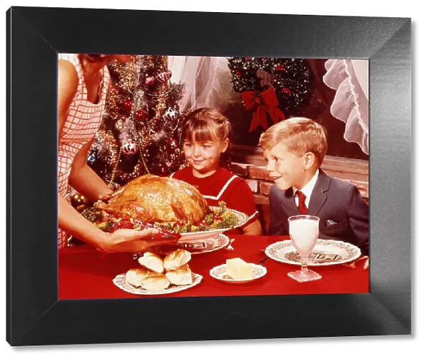 Mother showing roast turkey to children (7-10) at Christmas meal