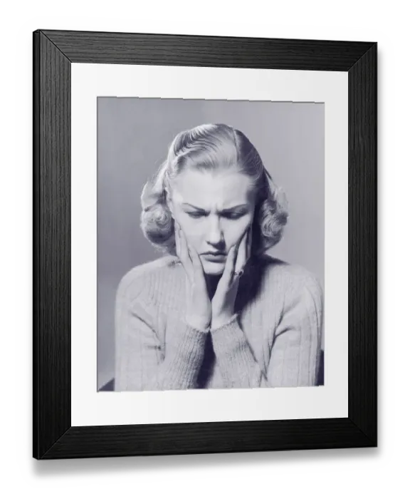 Framed Print : Woman frowning, holding hands to face (B&W) Framed Print : Woman frowning, holding hands to face (B&W)