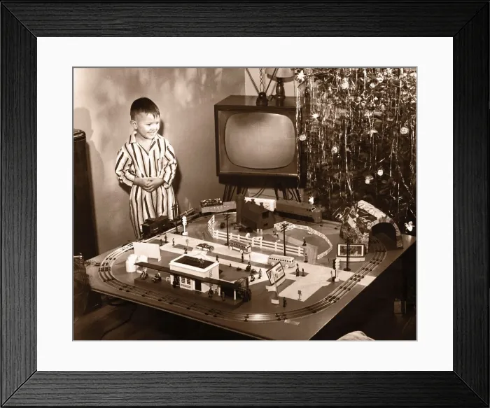 Framed Print : Boy (6-8) looking at model train set on Christmas Day(B&W sepia tone) Framed Print : Boy (6-8) looking at model train set on Christmas Day(B&W sepia tone)