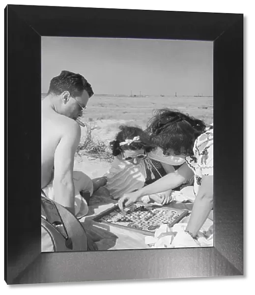 Man and two women playing chinese checkers at beach (B&W)