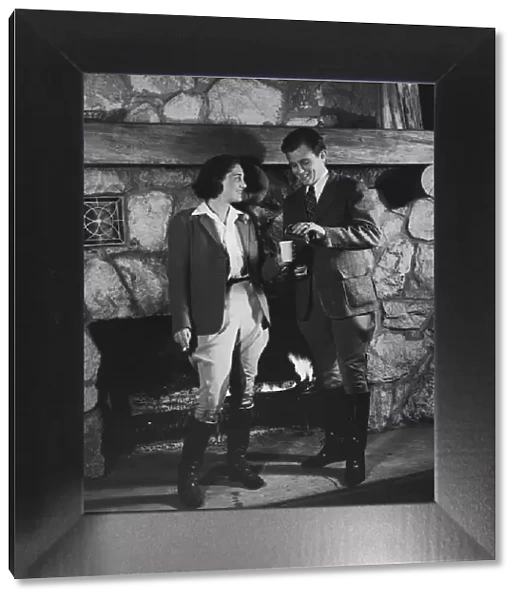Couple by fireplace wearing riding clothes (B&W)
