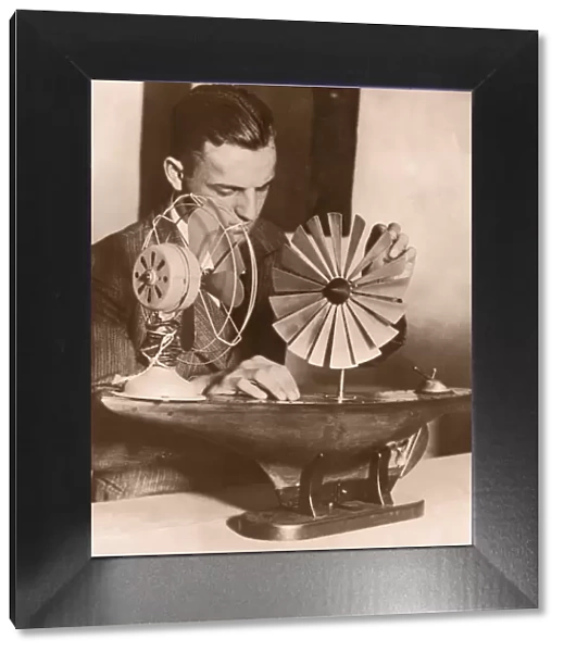 Man testing model of windmill ship propeller (B&W sepia tone)