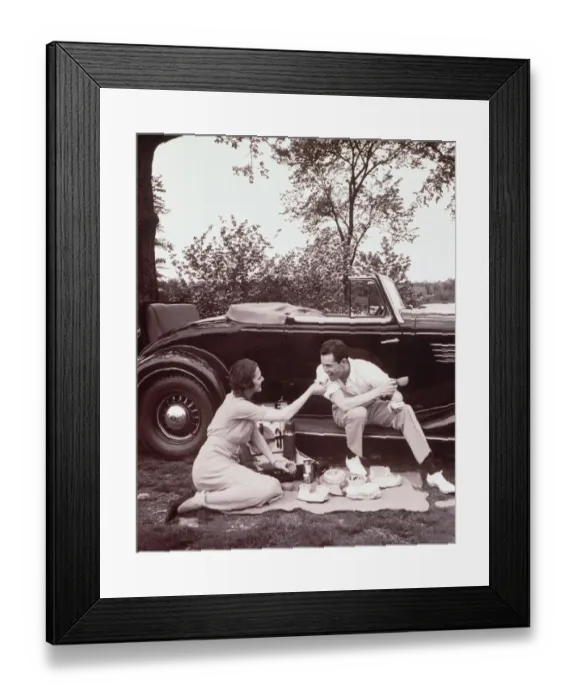 Framed Print : Couple picnicking, man sitting on car runningboard (B&W sepia tone) Framed Print : Couple picnicking, man sitting on car runningboard (B&W sepia tone)