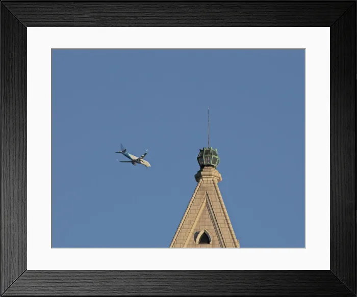 Framed Print : Flyby. A color photograph of a commercial jet flying past an older skyscraper Framed Print : Flyby. A color photograph of a commercial jet flying past an older skyscraper