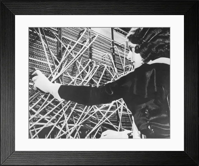 Framed Print : Female telephone switchboard operator connecting caller, close-up (B&W) Framed Print : Female telephone switchboard operator connecting caller, close-up (B&W)