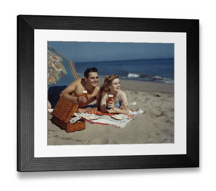 Framed Print : Young couple lying on beach with beer, smiling Framed Print : Young couple lying on beach with beer, smiling