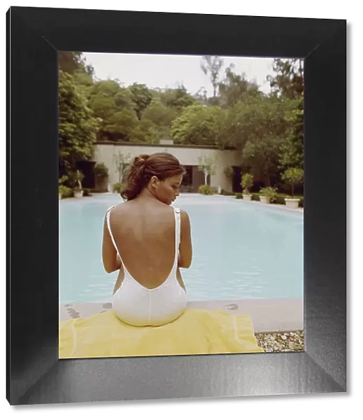 Young woman sitting at edge of swimming pool