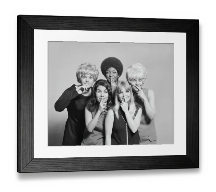 Framed Print : Friends with finger on lips standing against grey background, smiling, portrait Framed Print : Friends with finger on lips standing against grey background, smiling, portrait