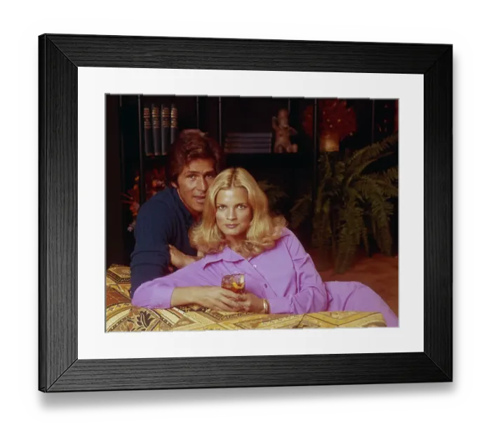 Framed Print : Young couple leaning on sofa, woman holding glass