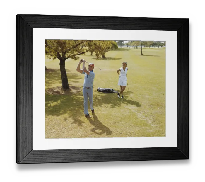 Framed Print : Mature couple playing golf, man swinging golf club Framed Print : Mature couple playing golf, man swinging golf club