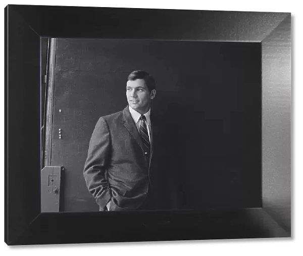 Businessman standing against black background, smiling