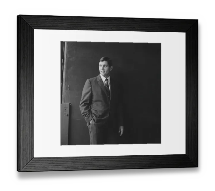 Framed Print : Businessman standing against black background, smiling Framed Print : Businessman standing against black background, smiling
