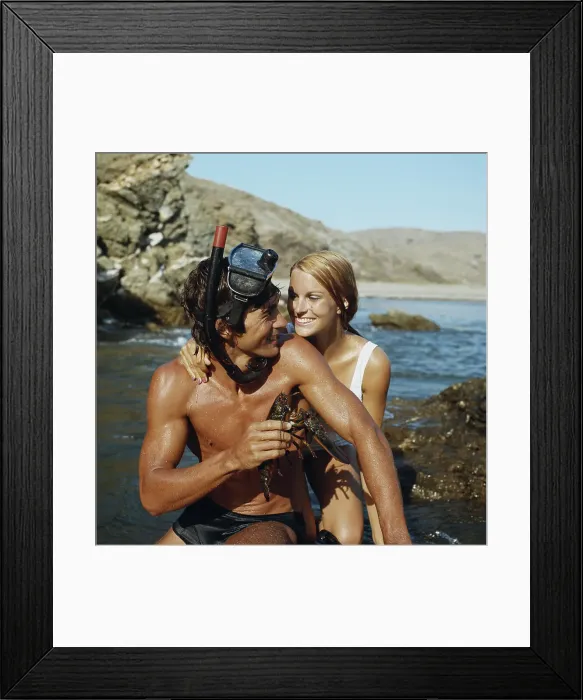 Framed Print : Man wearing snorkel, holding lobster beside woman, smiling Framed Print : Man wearing snorkel, holding lobster beside woman, smiling