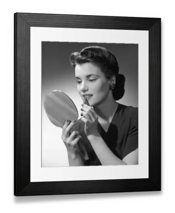 Framed Print : Woman applying lip-stick looking in hand-held mirror Framed Print : Woman applying lip-stick looking in hand-held mirror