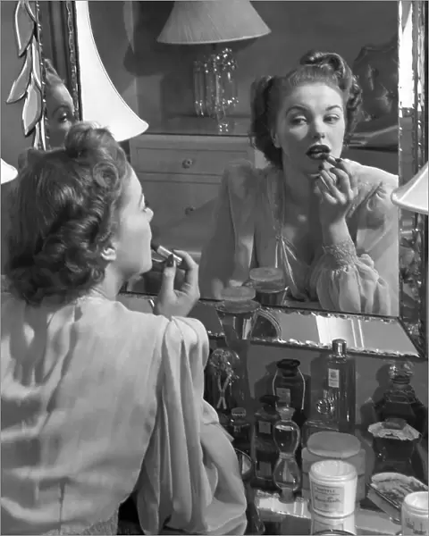 Woman applying lip-stick in front of mirror