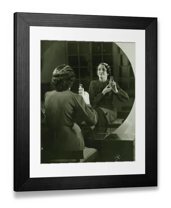 Framed Print : Young woman applying perfume in front of mirror, (B&W) Framed Print : Young woman applying perfume in front of mirror, (B&W)