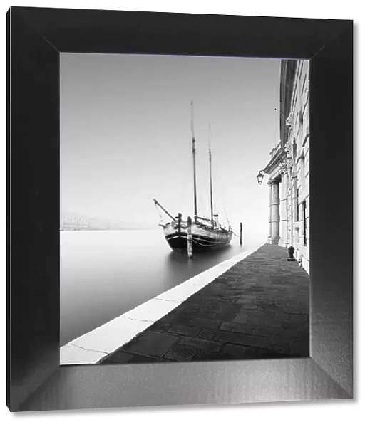 Black and white photograph of the Fondamenta Salute in the fog with a historic sailing ship in Venice, Italy