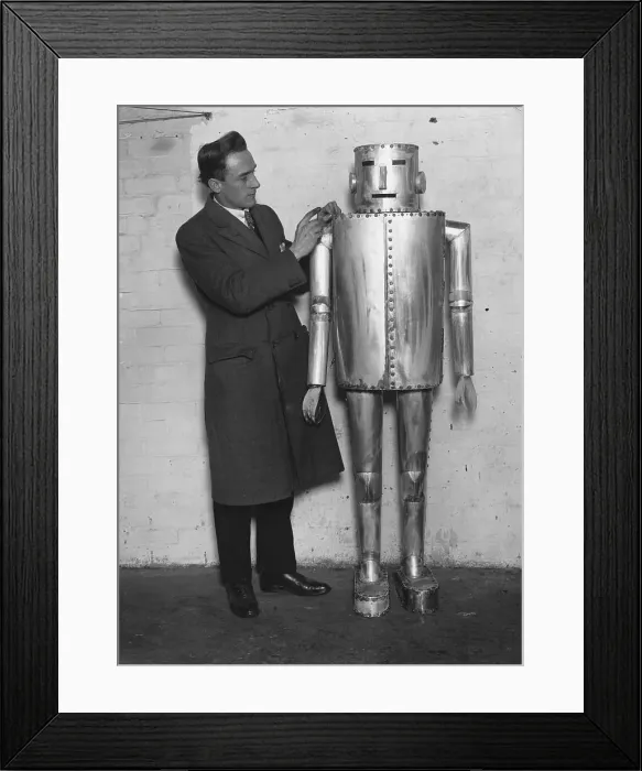 Framed Print : Iron Man. circa 1930: A man stands next to a primitive robot Framed Print : Iron Man. circa 1930: A man stands next to a primitive robot